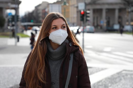 Young woman walking in city street wearing KN95 FFP2 face mask protective. Copy space.