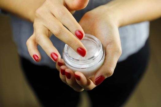 Close up female hands applying moisturizing cream 