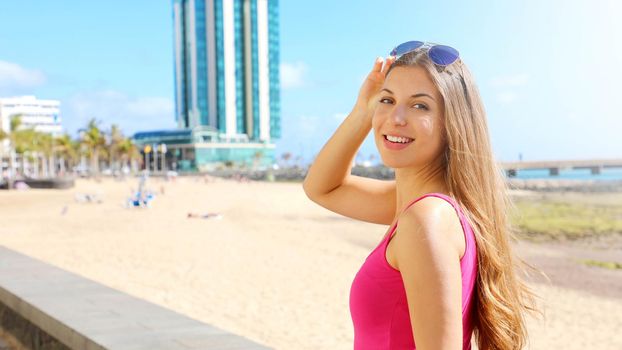 Travel Europe summer holiday girl enjoying Arrecife, Lanzarote, Canary Islands. Sun getaway woman smiling with sunglasses on her head.