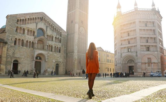 Tourism in Parma. Back view of young woman visiting the beautiful city of Parma in Italy. Traveler girl in Piazza Duomo square of Parma the Italian Capital of Culture 2020.