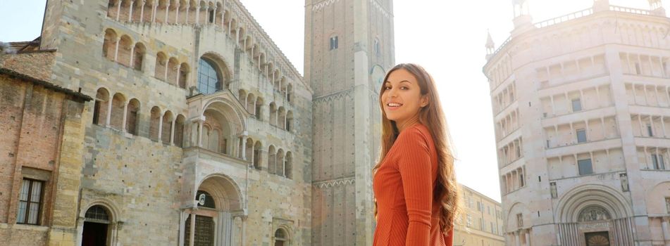 Portrait of beautiful tourist woman in Parma with Cathedral, Bell tower and Baptistery. Panoramic view of traveler girl with Parma landmark in Italy. Parma is Italian Capital of Culture 2020.