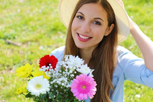 Romantic young woman holds bouquet of flowers in spring time outdoors