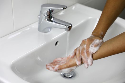 COVID-19 Washing hands with soap under running water  on sink. Hygiene and promotion of cleanliness and health against Novel coronavirus (2019-nCoV). Antiseptic, Hygiene and Healthcare concept.