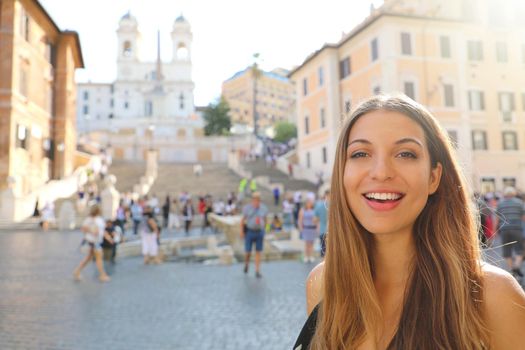 Close up of beautiful cheeful woman in Piazza di Spagna square in Rome with Spanish Steps and Barcaccia fountain on the background.