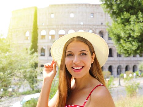 Portrait of smiling beautiful tourist girl in Rome with Colosseum on the background. Summer holidays in Italy.