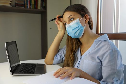 COVID-19 Pandemic Coronavirus Doubt Student Girl Home Schooling E-learning Mask Study from Home Laptop. Distance learning quarantine young woman studying from home for virus disease 2019-nCoV. 