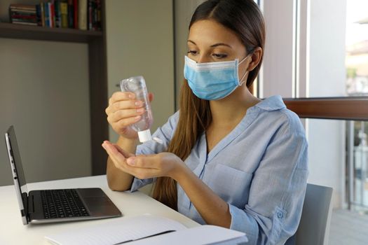 COVID-19 Pandemic Coronavirus Woman with Surgical Mask Working from Home using Alcohol Gel from Dispenser, against 2019-nCoV. Home Working, Auto Quarantine, Antiseptic, Hygiene and Healthcare concept.