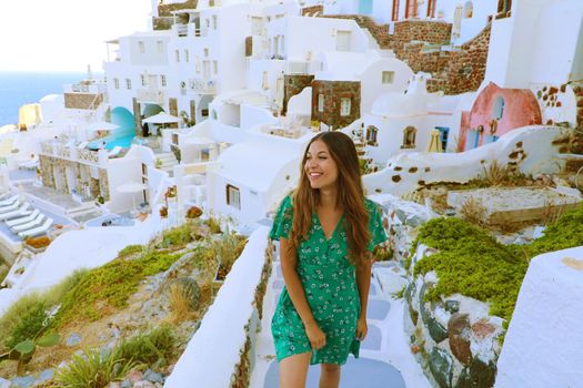 Vacation in Santorini. Happy tourist girl visiting Cyclades Islands, Greece. Young woman on summer holidays discovering Oia famous tourist resort in Santorini.
