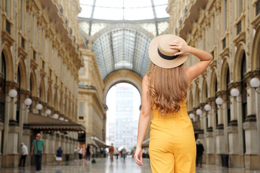 Fashion tourist woman stops to look enchanted Vittorio Emanuele Gallery in Milan, Italy. Travel girl enjoy visiting the city center of Milan famous destination for tourism and fashion.
