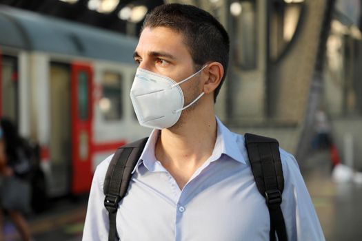 Portrait of man waiting train with KN95 FFP2 protective mask at train station