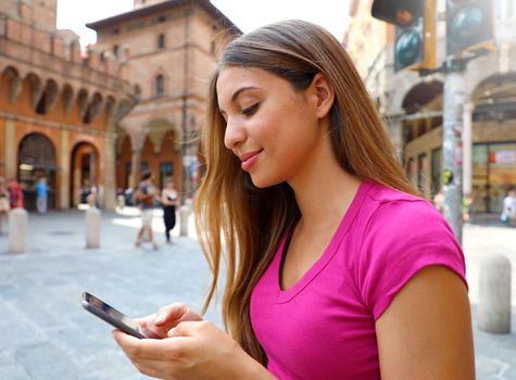 Portrait of smiling woman using smart phone in old medieval town