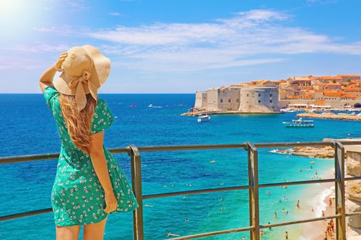 Attractive woman with green dress enjoys the view of the old town of Dubrovnik, Croatia