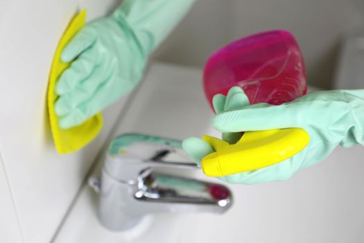 Female hands cleaning the bathroom with spray and sponge.