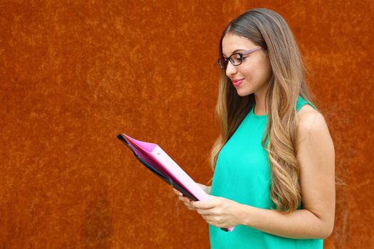 Professor female or business woman reading documents outdoor with copy space on rust background.