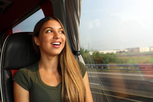 Happy cheerful smiling woman enjoying her travel on bus. Looking through the window.