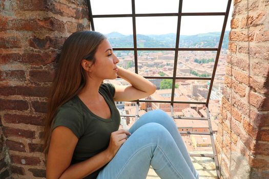 Europe travel woman looking at Bologna cityscape from the top of Asinelli tower, famous medieval tourist attraction in Italy