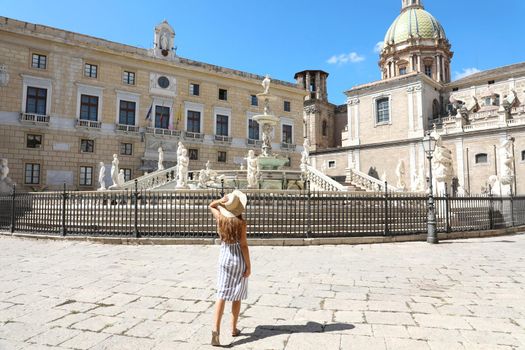 Travel in Sicily. Back view of young beautiful woman walking near the monumental Praetorian Fountain in Palermo, Italy.