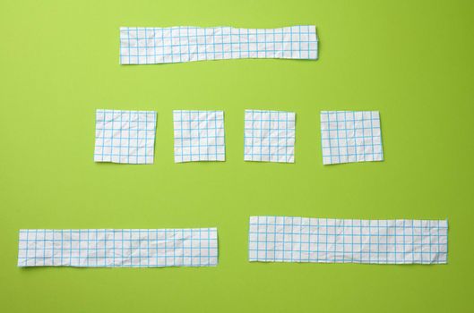 various pieces of white paper in a blue cage on a green background