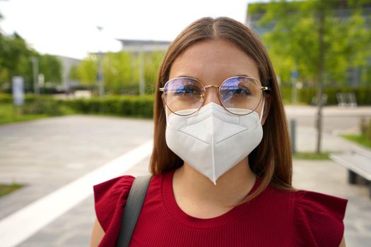 Close up portrait of young woman wearing glasses and protective mask KN95 FFP2 outside