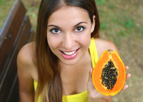 Close up of brazilian woman showing papaya healthy fruit outdoor.