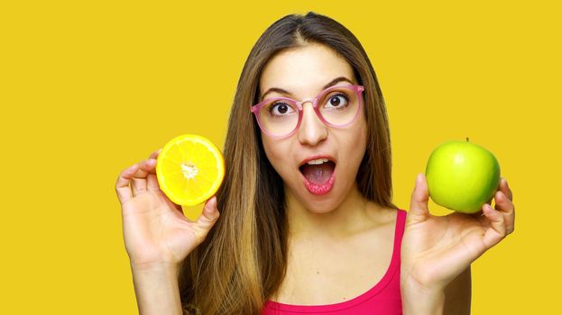 Happy funny girl presenting fruits against orange background