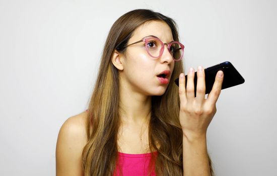 Serious girl using voice recognition app on smart phone 