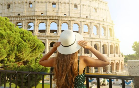 Travel in Italy. Back view of beautiful girl visiting Colosseum landmark at sunset in Rome. Summer holidays in Europe.