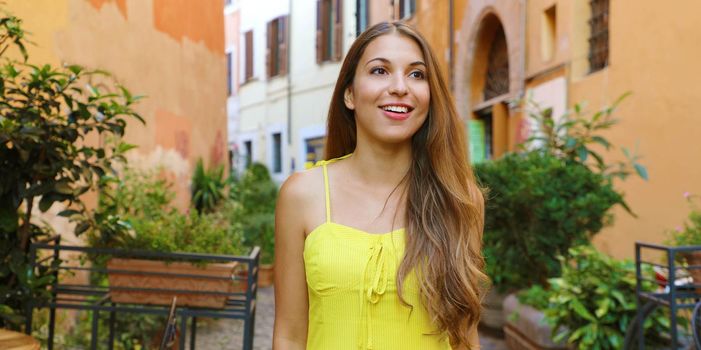 Portrait of beautiful young woman in yellow summer dress walking and exploring Trastevere neighborhood in Rome, Italy. Panoramic banner view.