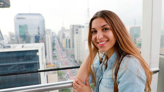 Attractive city woman over the rooftops of Sao Paulo with view to the skyline and the Paulista Avenue, Brazil