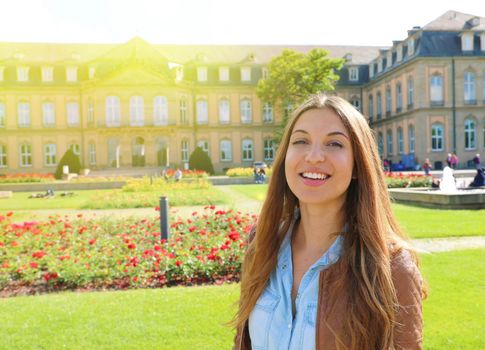 Smiling cheerful young woman in front of Neues Schloss (New Palace) of Stuttgart, Germany.