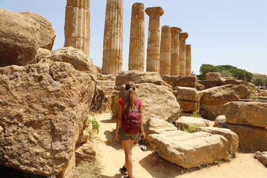 Young woman walking in the Valley of the Temples of Agrigento, Sicily. Traveler girl visits Greek Temples in Southern Italy.