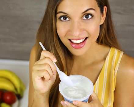 Brazilian woman eating light yogurt at home. Close up from above. Healthy concept.