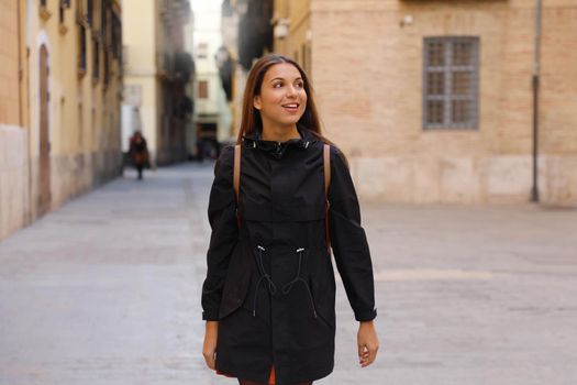 Curious girl travelling and visiting Europe in winter time. Backpacker girl walking in Valencia admiring spanish architecture.