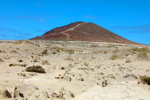 A view of Montana Roja volcano with sand desert in El Medano, Tenerife, Spain