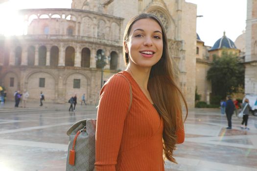 Portrait of beautiful tourist woman in Valencia with Cathedral on the background. Smiling traveler girl with Valencia landmark in Spain.