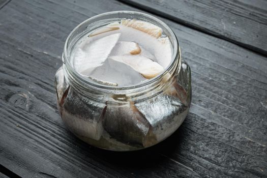 Icelandic herring, in glass jar, on black wooden table background