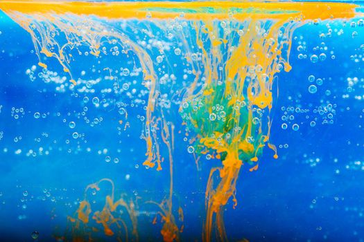 Splashes of paint dissolve swirling in water