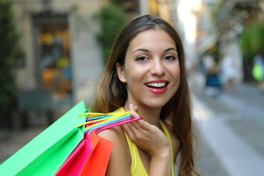 Close up of cheerful young woman holding shopper bags in Brera neighborhood, Milan, Italy