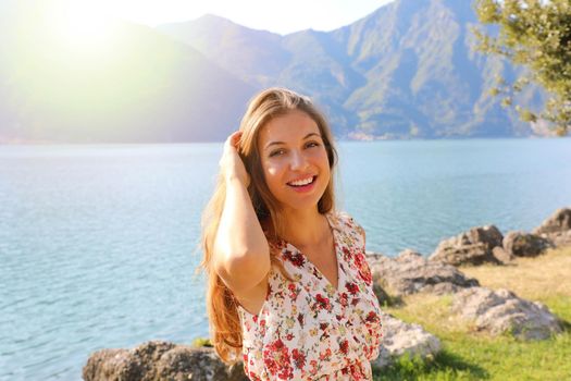 Portrait of happy beautiful woman on lake with flare sunlight