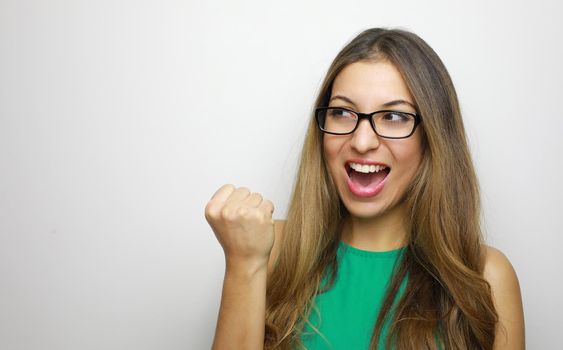 Self determined woman with glasses looking to the side with clenche fist and exclaims with triumph expression, cheers about something good, screams: Yes, I did it finally! People and body language.