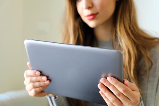 Young cheerful woman holding tablet at home, focus on the tablet