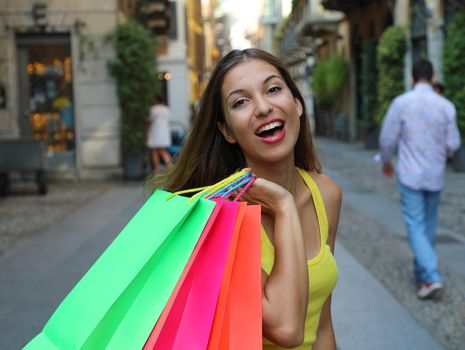 Close up of cheerful young woman holding shopper bags in Brera neighborhood, Milan, Italy