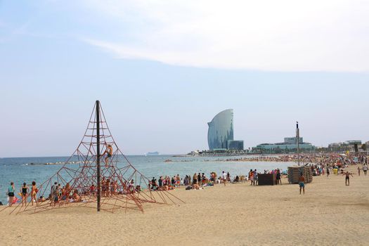 BARCELONA, SPAIN - JULY 11, 2018: amazing view of Barceloneta beach with people enjoying sunny day in Barcelona and W hotel on background, Catalonia, Spain