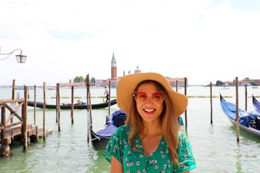 Smiling woman with sunglasses and hat looking at camera with Venice Lagoon on the background