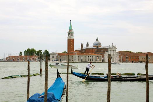 VENICE, ITALY - JULY 18, 2018: tourists on gondola with gondolier in Venice Lagoon, Italy