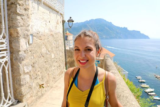 Young smiling traveler woman in Atrani village, Amalfi Coast, Italy. Tourist girl in her summer holidays in southern Italy.