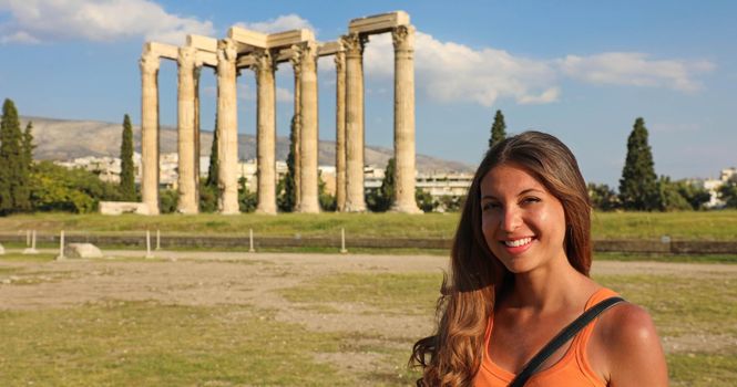 Smiling tourist woman with the greek temple of Olympian Zeus on the background, Athens, Greece. Panoramic banner crop.
