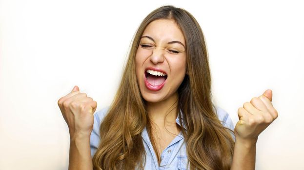 We did it! Portrait of closed eyes raised fists up woman in casual wear isolated on white background.