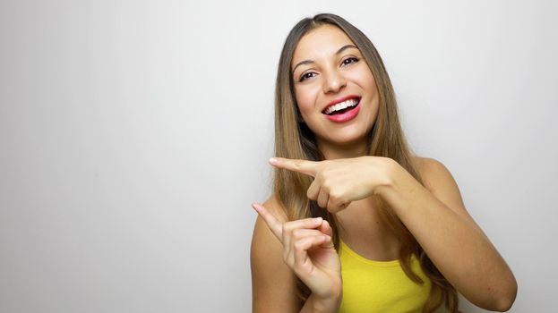 Smiling casual girl pointing finger on copy space