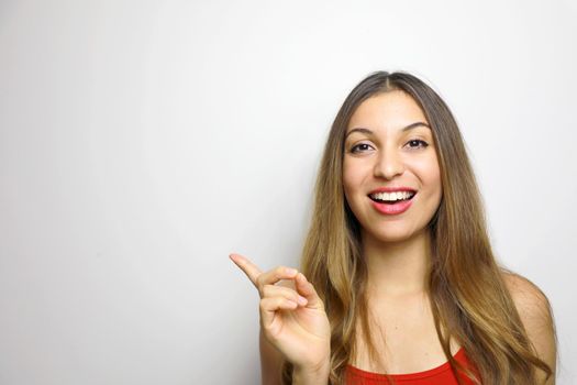 Smiling young woman pointing finger on white background